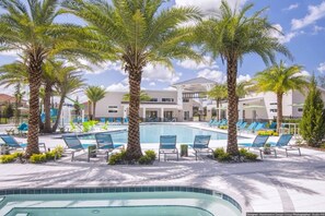 A resort pool area with palm trees, lounge chairs, and a modern building in the background.