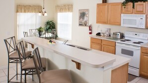 A kitchen with a central island, wooden cabinets, a microwave, and a stove. - Ip60154 - Highgate at Legacy Park - 5 Bed 3.5 Baths Villa (Davenport)