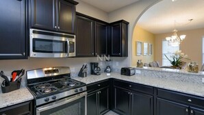 A modern kitchen with dark cabinetry, stainless steel appliances, and a marble countertop. - Fv61774 - Solterra Resort - 5 Bed 4.5 Baths Villa (Davenport)