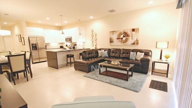 A modern living room with a sofa, coffee table, and a dining area with chairs and a table.