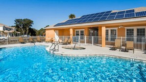 A swimming pool with lounge chairs and a building with solar panels.