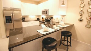 A modern kitchen with a central island, stainless steel appliances, and pendant lighting.