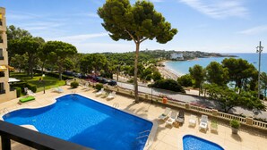 Ein Swimmingpool mit Liegestühlen, einem Baum und Blick auf den Strand.