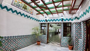 Un patio con paredes decoradas, suelo de baldosas y una puerta de madera.