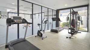 Un gimnasio moderno con cintas de correr, elípticas y una máquina de pesas.