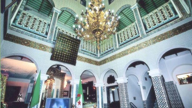 Un interior con una gran araña, techos abovedados y paredes con baldosas estampadas.