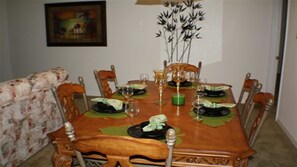 A dining room with a wooden table set for four, surrounded by chairs.