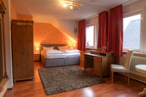 Un dormitorio con cama, escritorio, silla y radiador.