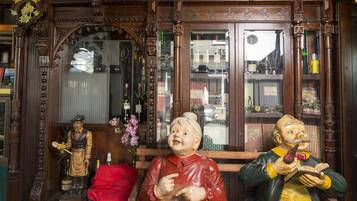 A wooden interior with ornate carvings, a bench, and two statues.