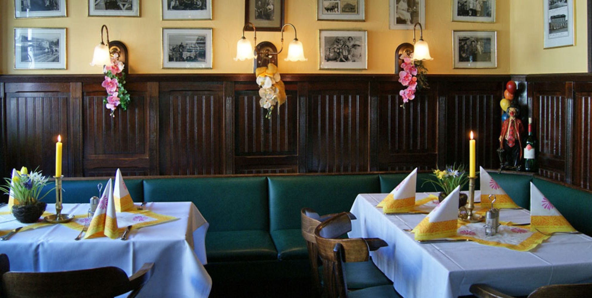 Ein Restaurant mit Sitzecken und Tischen, an jedem Tisch eine Kerze und eine Blumenarrangemement.