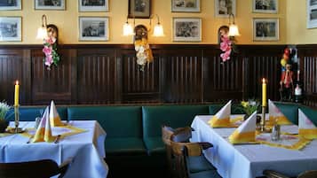 Ein Restaurant mit Sitzecken und Tischen, an jedem Tisch eine Kerze und eine Blumenarrangemement.