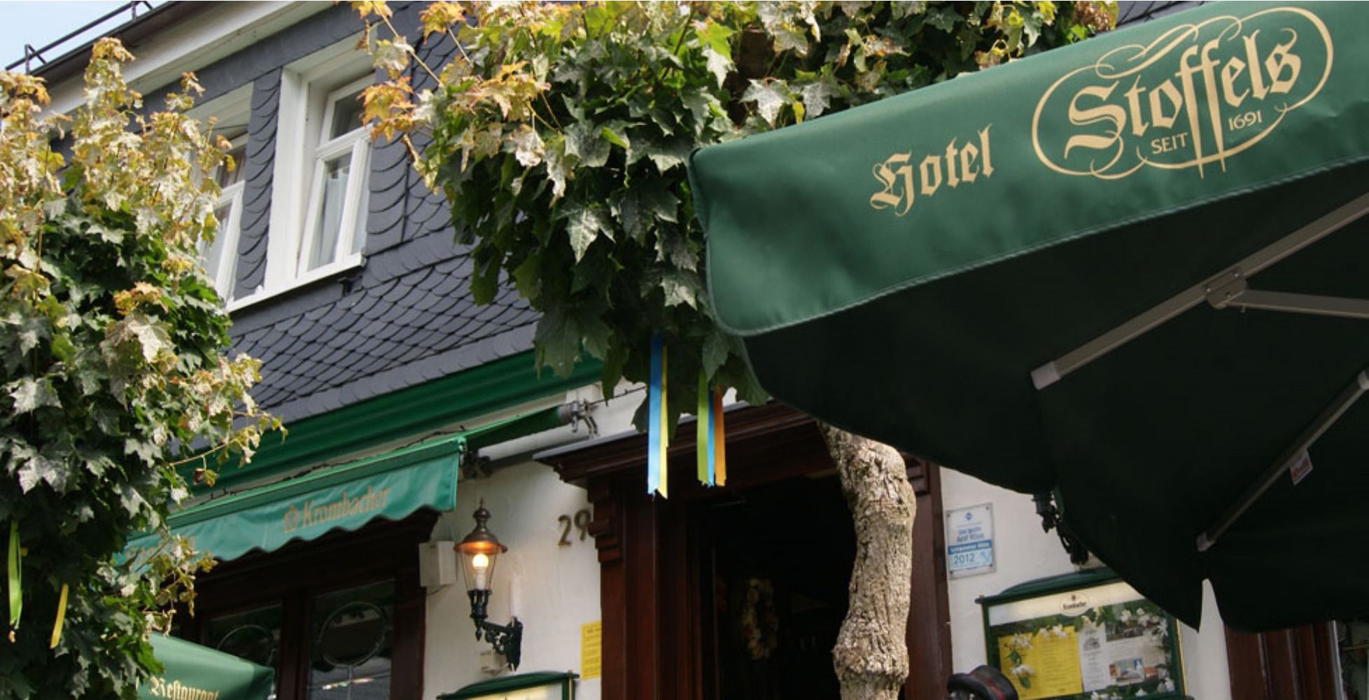 A hotel entrance with a green awning and a sign reading "Hotel Stoffels."