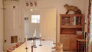 A dining room with a table set for four, candles, a fox statue, and a wooden cabinet with glass doors.