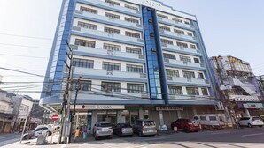 Un edificio de varios pisos con fachada azul y blanca, que cuenta con varios locales comerciales a nivel de calle, incluyendo un banco y un restaurante.