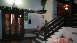 A staircase leading to a second floor, a bench, and a wall decorated with a garland and a heart-shaped ornament. - Hotel Panorama (Cavalese)