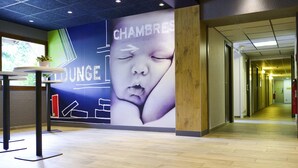 Un moderno vestíbulo con área de descanso, un mural grande en la pared y un mostrador de recepción de madera.