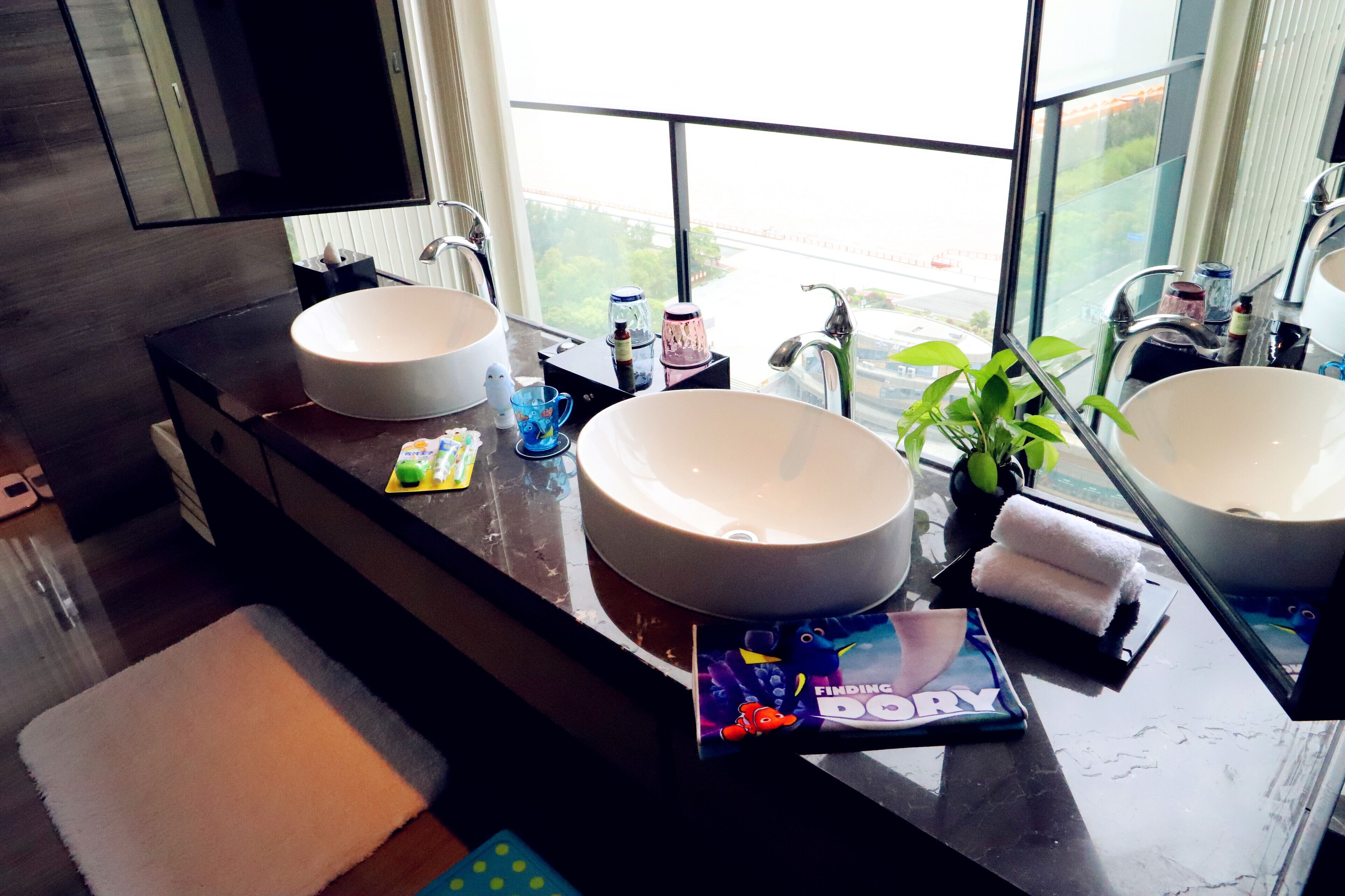 Un baño moderno con dos lavamanos grandes, un espejo y una ventana con vistas al exterior.