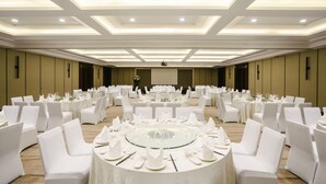 A banquet hall with round tables set for a formal event, featuring white chairs and a central glass table. - Pullman Zhoushan Seaside (Zhoushan)