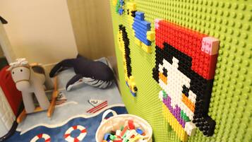 A LEGO wall with a pixelated character, a bucket of LEGO pieces, and a toy horse.