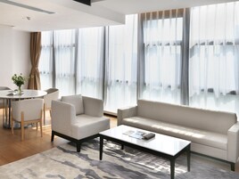 Una sala de estar moderna con un sofá, sillones, una mesa de centro y un comedor con una mesa y sillas.