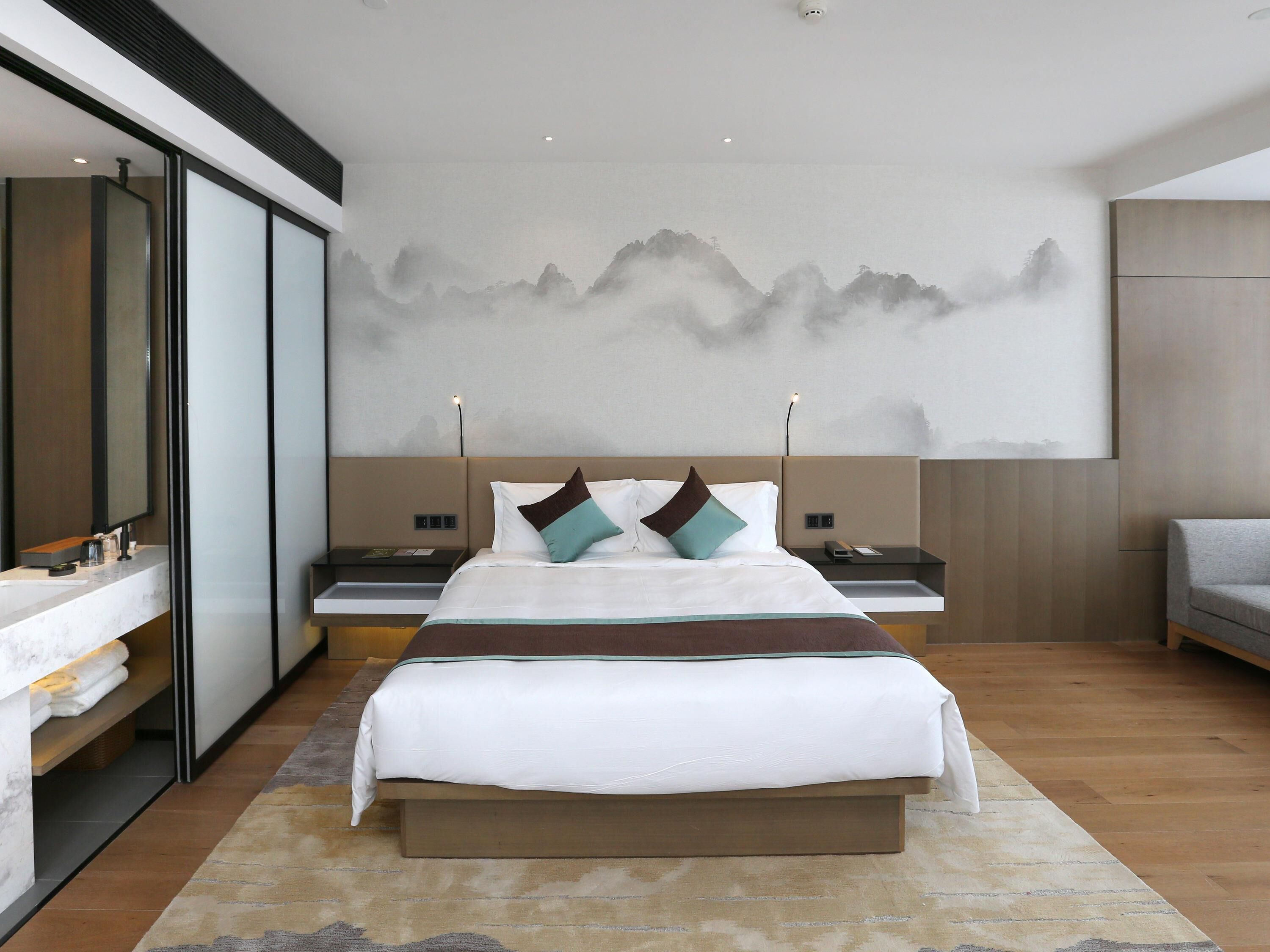 Un dormitorio moderno con una cama grande, mesitas de noche, un espejo y un mural en la pared.