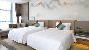Habitación de hotel con dos camas, un sofá y un mural grande en la pared.