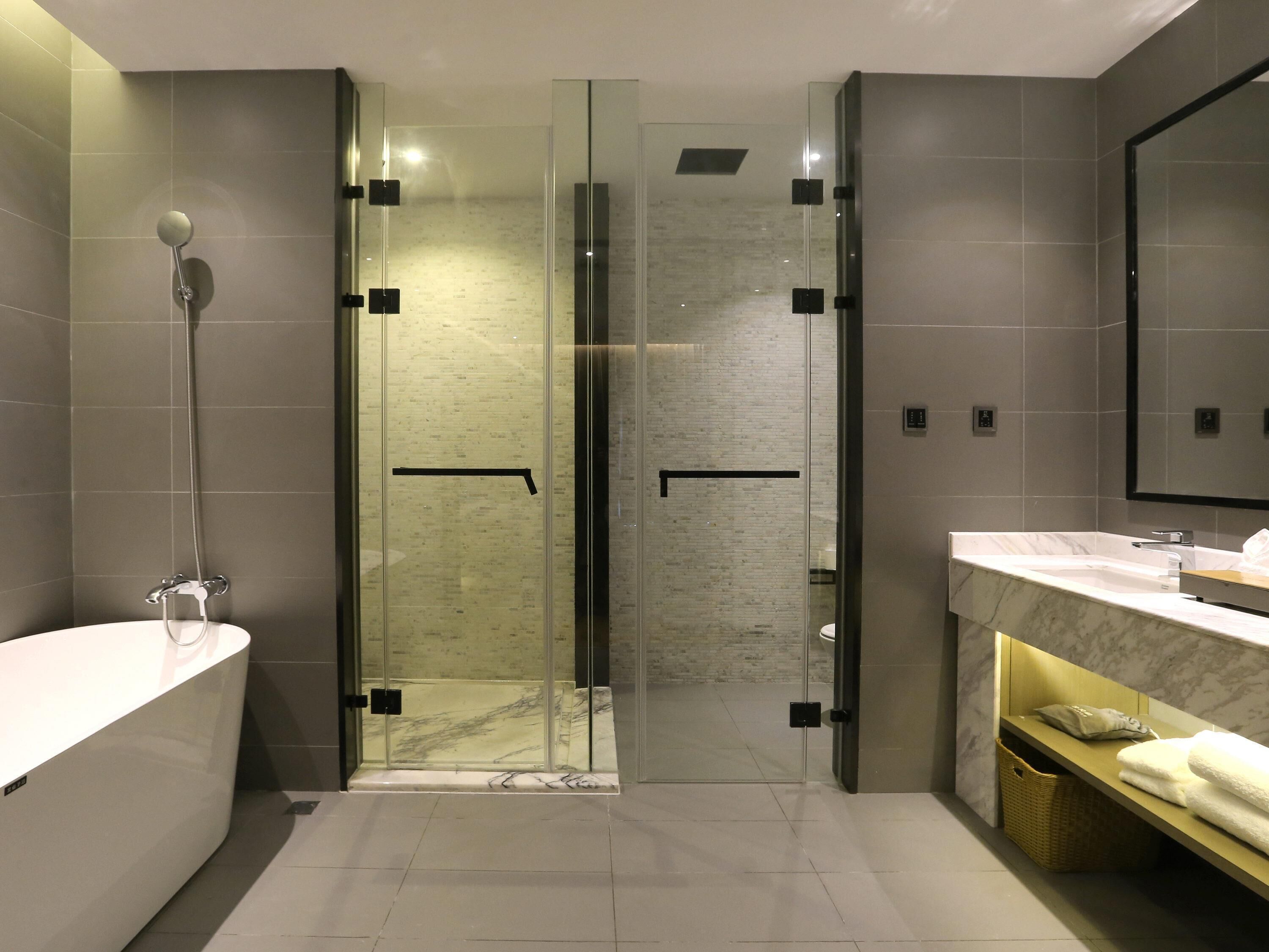 A modern bathroom with a glass-enclosed shower, a white bathtub, and a marble countertop.