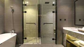 A modern bathroom with a glass-enclosed shower, a white bathtub, and a marble countertop.