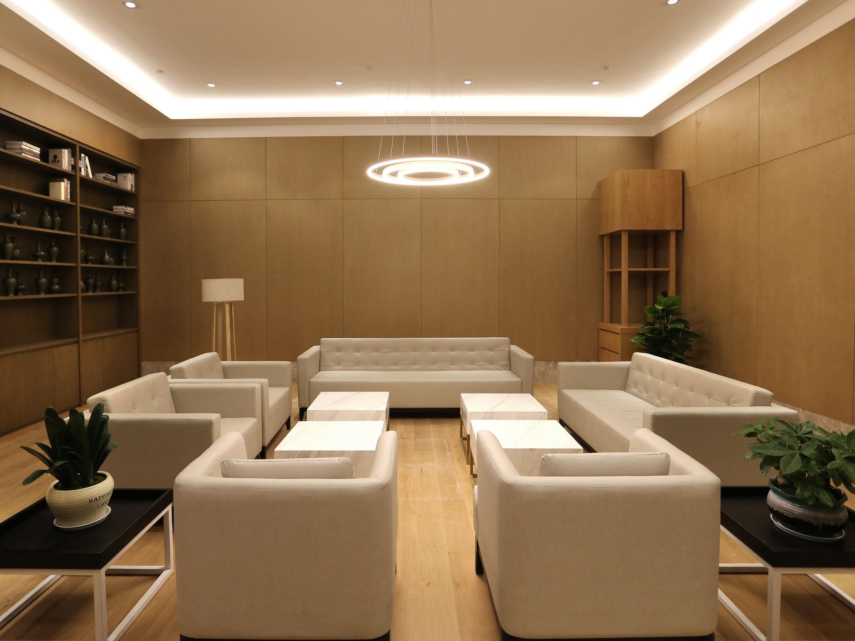 A modern living room with a sofa set, armchairs, a coffee table, a bookshelf, and a pendant light.