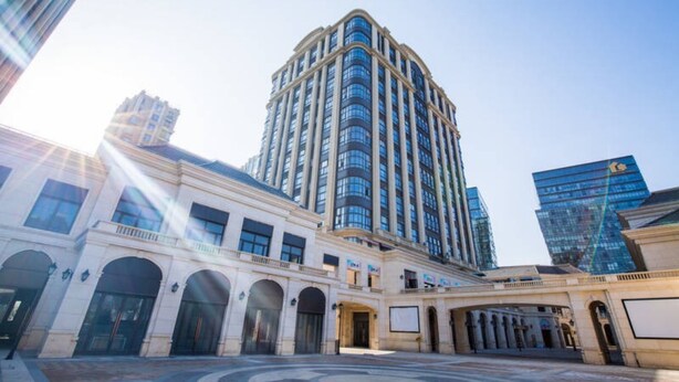 Un hôtel de grande hauteur à l’architecture classique, doté d’une cour intérieure avec des entrées en arc de cercle et d’un bâtiment moderne en verre attenant.