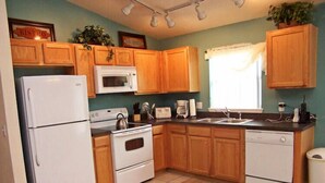 A kitchen with wooden cabinets, a white refrigerator, a microwave, a stove, a sink, and a dishwasher. - Fs54755 - Sandy Ridge - 4 Bed 3 Baths Villa (Davenport)