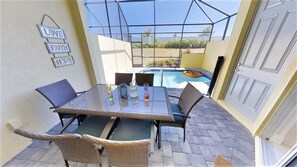 An outdoor patio with a glass table and wicker chairs, a pool, and a 'LOVE FAITH HOPE' sign. - Aco248528 - Festival Resort - 5 Bed 5.5 Baths Townhome (Davenport)