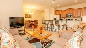 A living room with a TV, sofa, coffee table, and a dining area with chairs and a table. - Fv50095 - Paradise Palms - 4 Bed 3 Baths Townhome (Kissimmee)