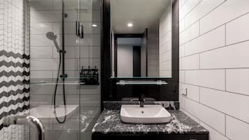 Ein modernes Badezimmer mit einer gläsernen Duschkabine, einem weißen Waschbecken und einer schwarzen Arbeitsplatte.