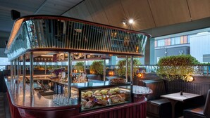 A bar area with a glass display case of pastries and a seating area with booths and tables. - Rydges Wellington Airport (Wellington)