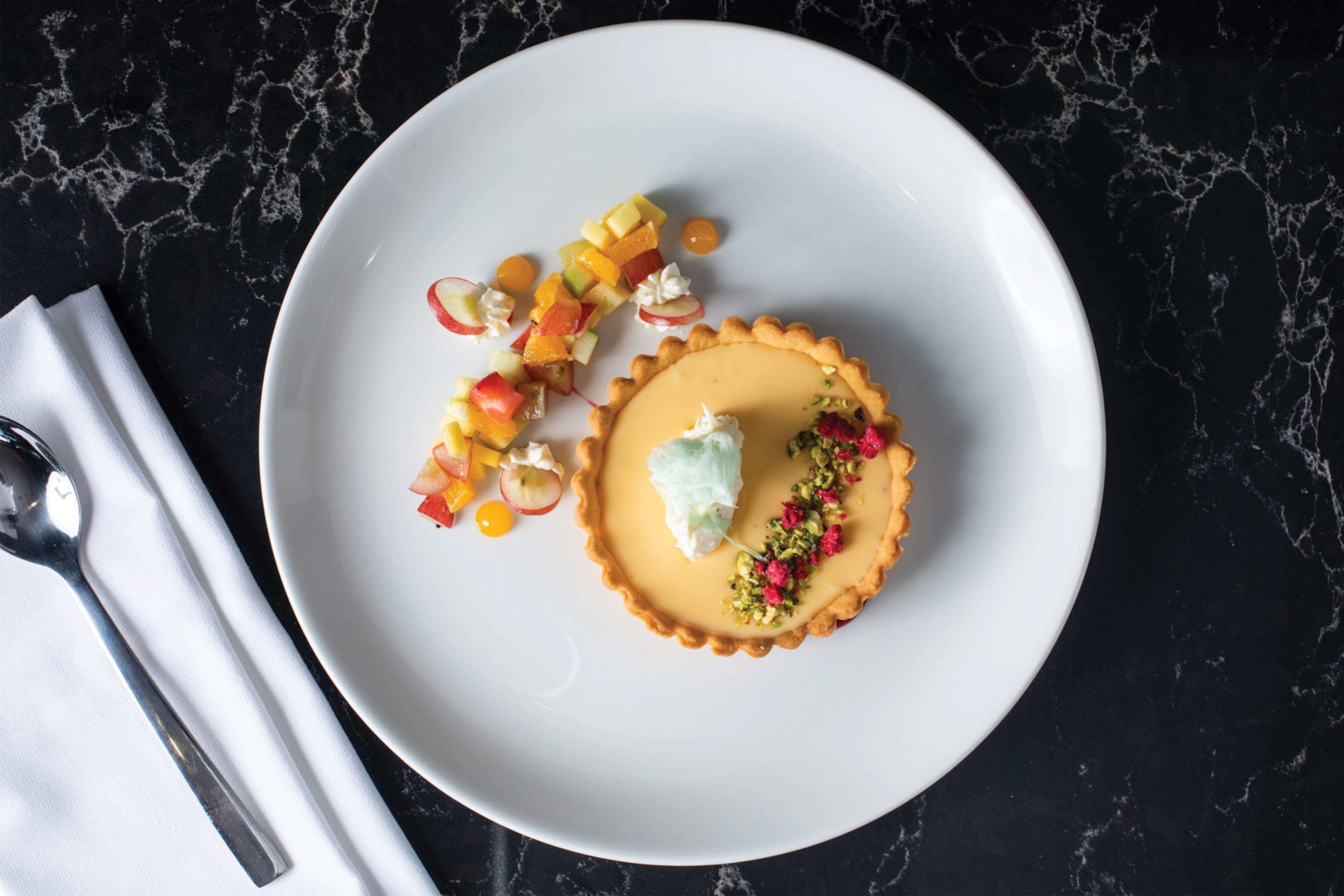Un postre sobre un plato blanco, con un fondo de mármol oscuro.