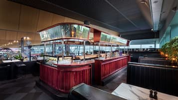 Un restaurante con barra curva, zona de estar y vistas a la ciudad.