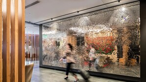 A modern interior with a large decorative wall, a wooden partition, and a seating area with chairs. - Rydges Wellington Airport (Wellington)