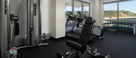 A gym with treadmills, dumbbells, and weight machines.