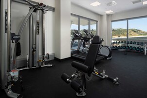 Un gimnasio con cintas de correr, mancuernas y máquinas de pesas.