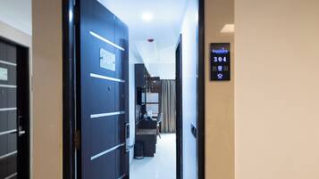 Entrada de una habitación de hotel con una puerta que da a un pasillo, una recepción y un lector de llave electrónica.