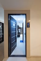 Entrada de una habitación de hotel con una puerta que da a un pasillo, una recepción y un lector de llave electrónica.