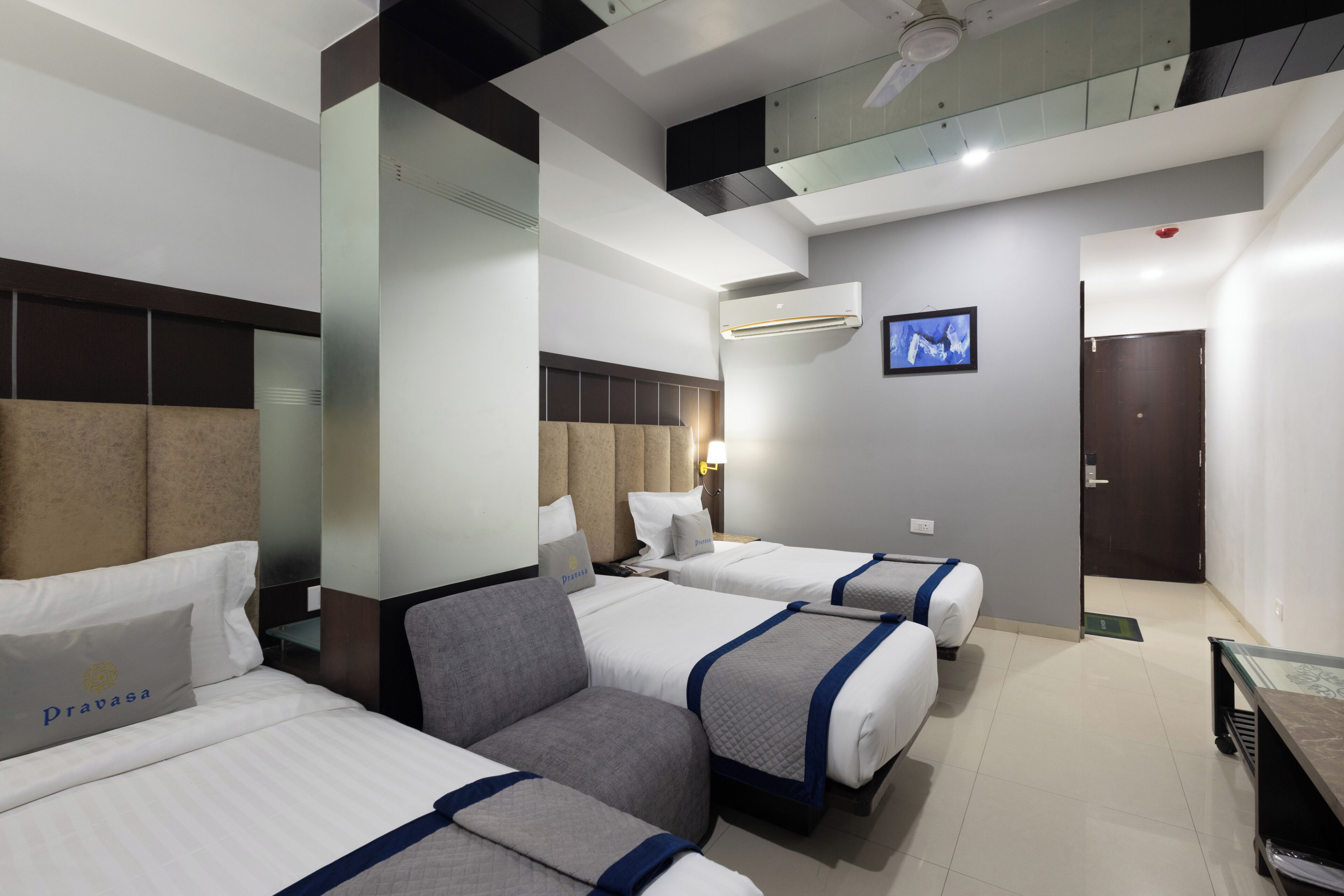 A hotel room with two beds, a sofa, a flat-screen TV, and a ceiling fan.