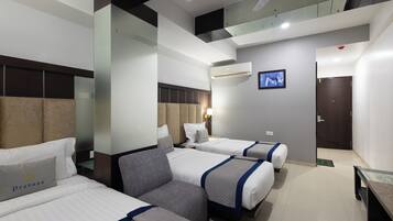 A hotel room with two beds, a sofa, a flat-screen TV, and a ceiling fan.