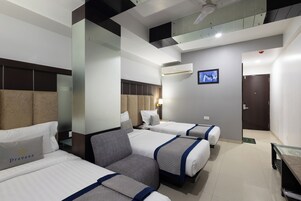 Habitación de hotel con dos camas, un sofá, un televisor de pantalla plana y un ventilador de techo.