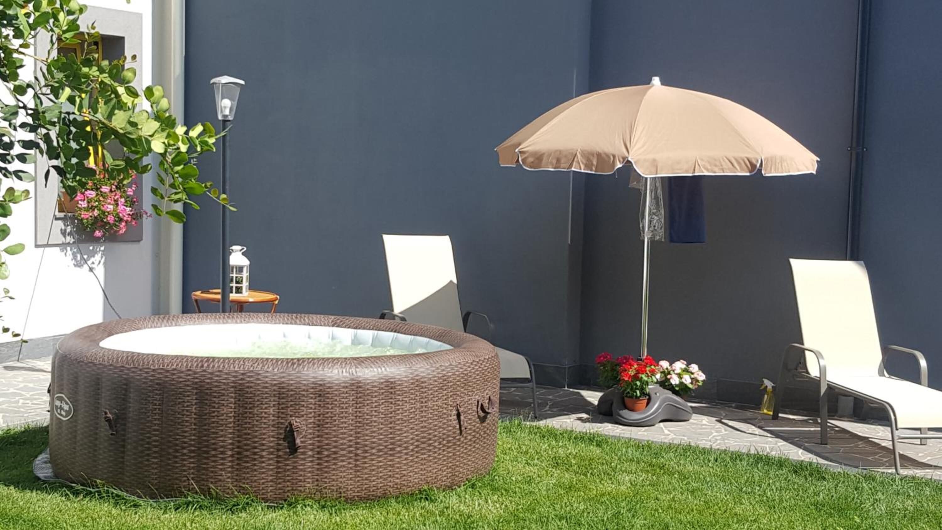 Ein Whirlpool in einem Garten mit Stühlen und einem Sonnenschirm.