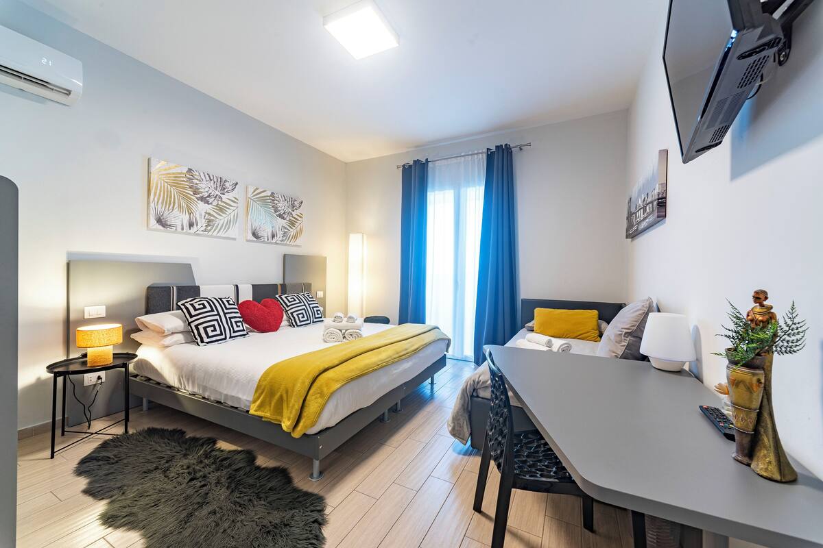 Une chambre d’hôtel moderne équipée d’un lit, d’une table de chevet, d’une lampe et d’un bureau avec une chaise.