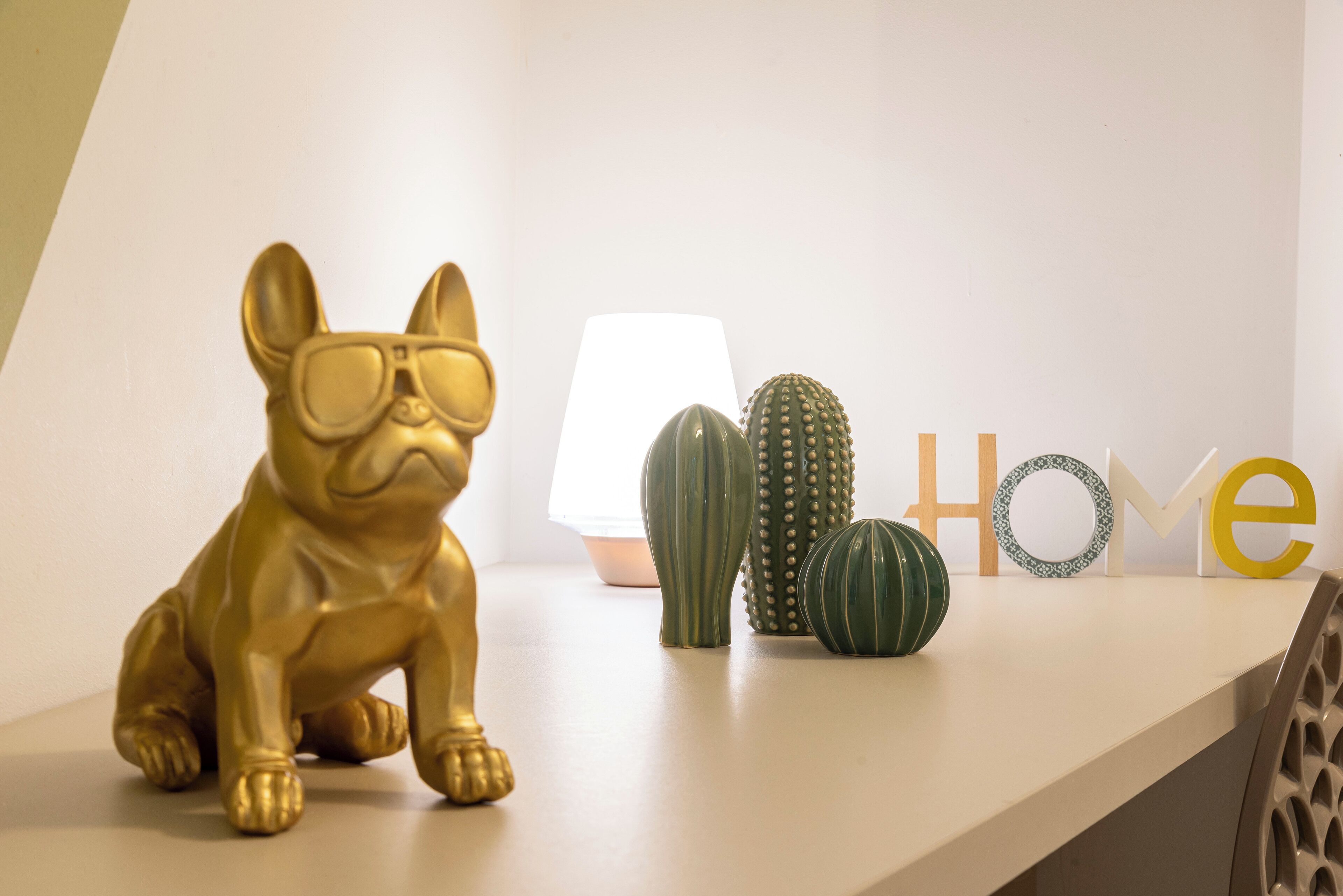 A gold dog figurine, a lamp, and decorative cacti on a white shelf.