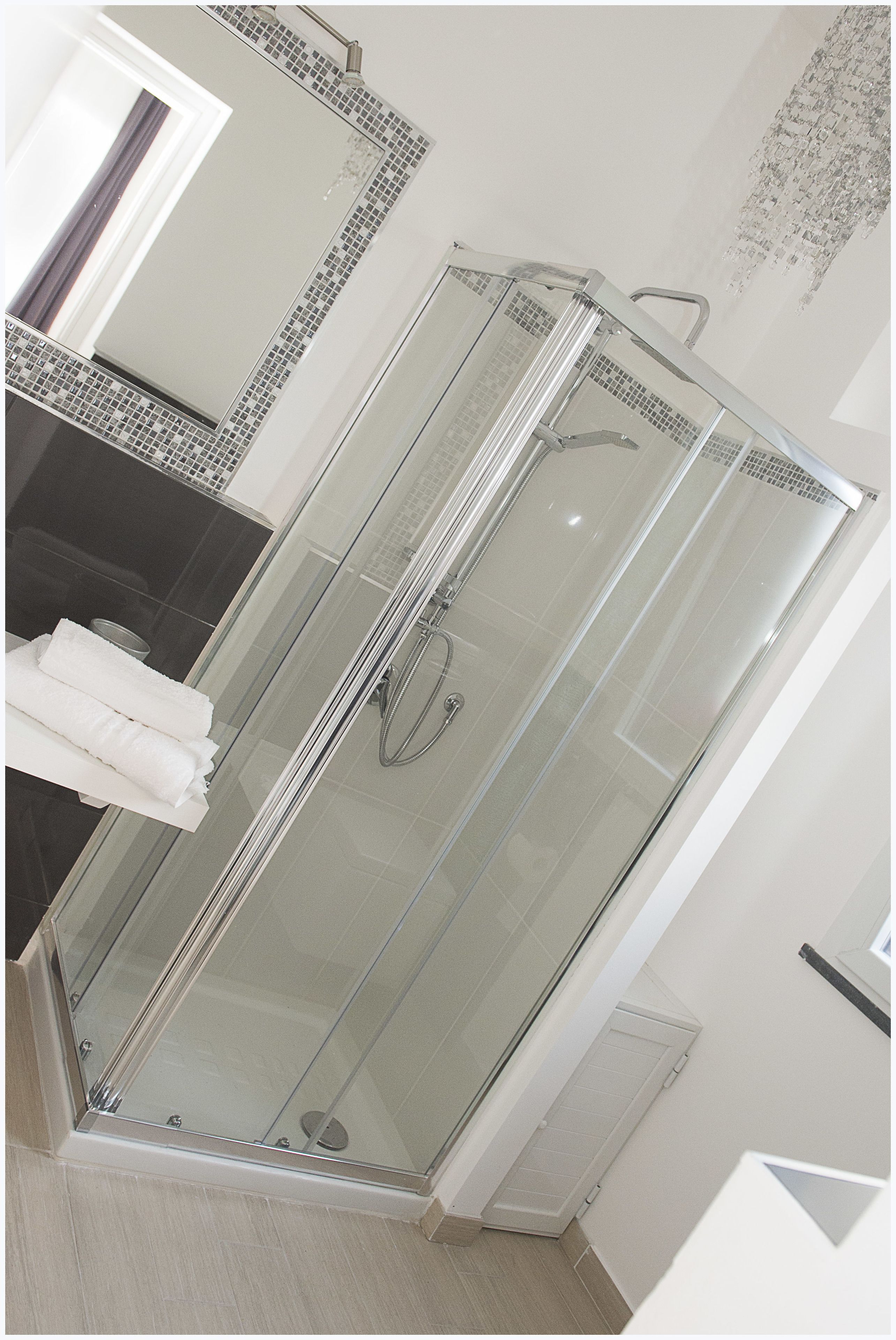 Un baño moderno con ducha de vidrio, lavamanos blanco y un perchero para toallas.