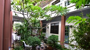 A courtyard with potted plants, a stone pathway, and a building with barred windows. - Nong Apartment Pattaya - Adults Only (Pattaya)